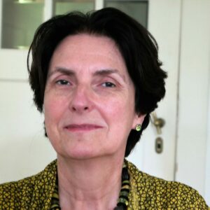 Mareille Hildebrandt sits in front of a door and smiles into the camera.