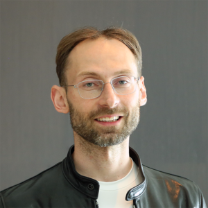 Michael Bronstein stands in front of grey wall and smile sin camera.